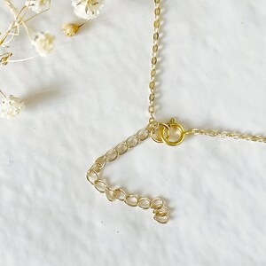 A gold chain necklace with a spring clasp closure. The chain is made of small, round links.
