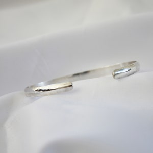 May include: A silver bangle bracelet with a smooth, rounded finish.