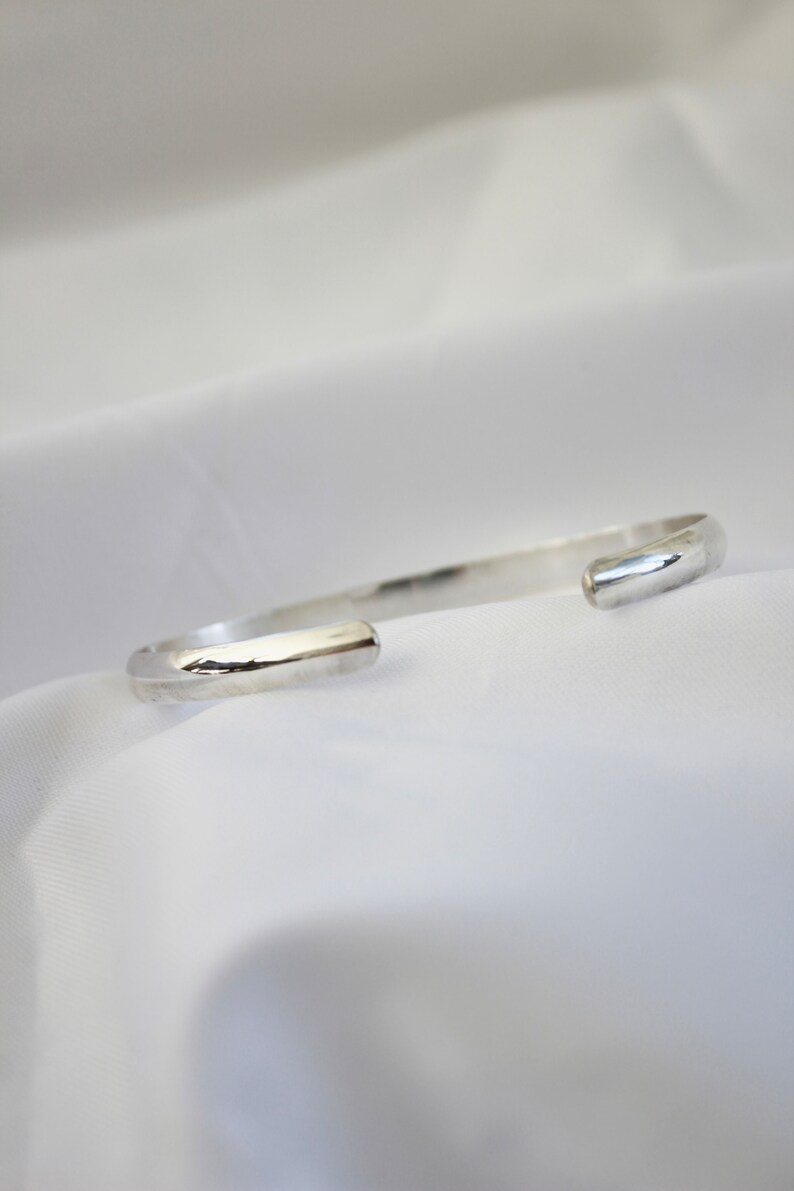 May include: A silver bangle bracelet with a smooth, rounded finish.