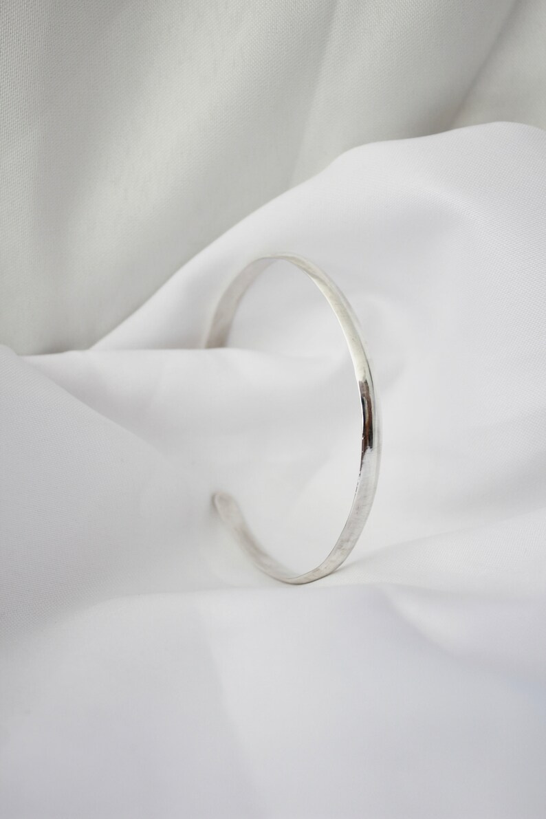 May include: A simple silver bangle bracelet with a smooth, polished finish.