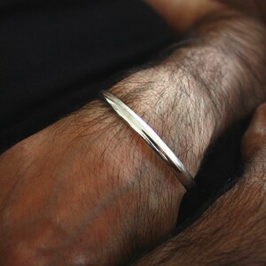 May include: A silver bangle bracelet on a person's arm.
