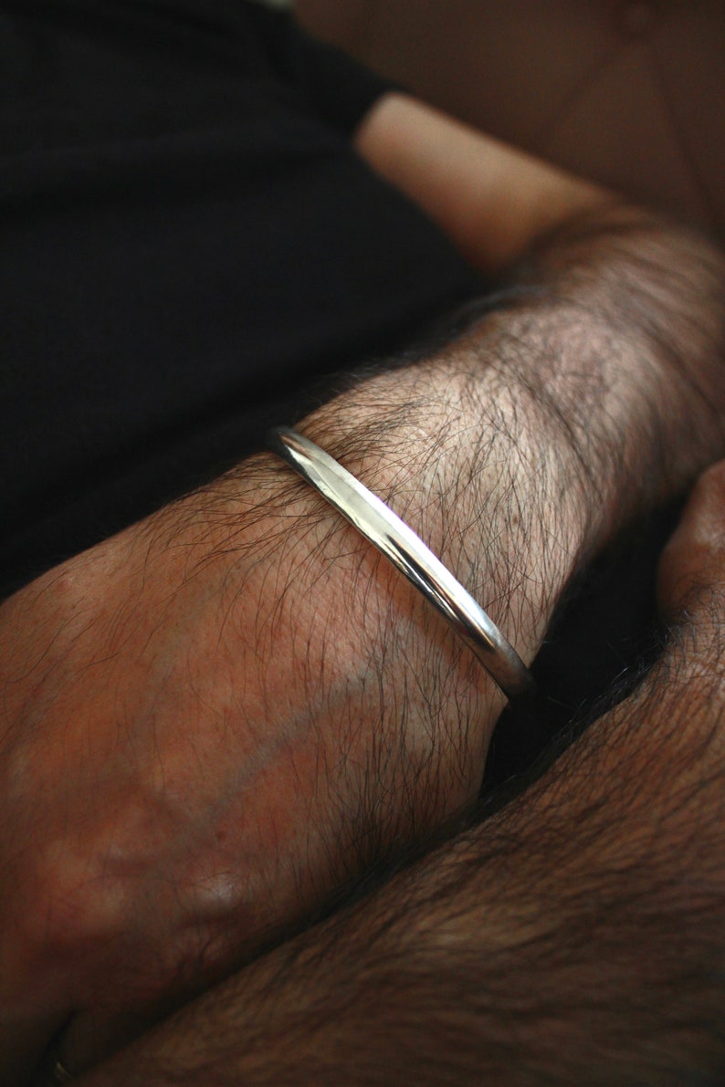 May include: A silver bangle bracelet on a person's arm.