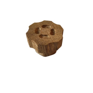 May include: A wooden knob with a starburst shape and three holes in the centre. The knob is a light brown colour.