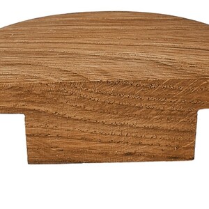 Könnte beinhalten: Ein halbrunder Holzpfosten mit T-förmigem Sockel. Der Pfosten ist aus naturbelassenem Holz in hellbrauner Farbe.