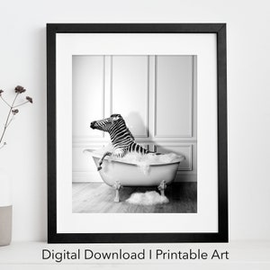 Pode incluir: Fotografia a preto e branco de uma zebra a tomar banho numa banheira branca com bolhas. A zebra está sentada na banheira com a cabeça e o pescoço fora da água. A banheira está num chão de madeira numa casa de banho com azulejos brancos.