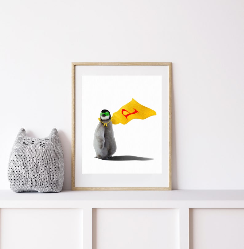 May include: A framed illustration of a penguin wearing a yellow cape with a red letter 'P' on it. The penguin is wearing a green mask and has a yellow band around its neck. The background is white.