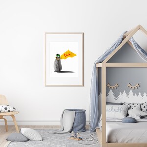 May include: A framed print of a penguin wearing a yellow cape with a red letter 'P' on it. The penguin is standing on a white background.