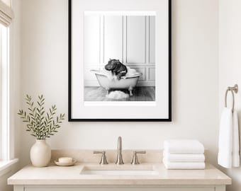 May include: A black and white framed wall art print featuring a small hippopotamus sitting inside a clawfoot bathtub filled with white soap bubbles. The hippo is positioned in the center of the tub, surrounded by foam, against a paneled wall.