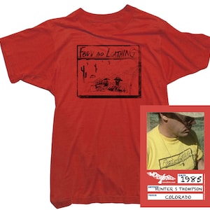 Puede incluir: Camiseta roja con un estampado gr&aacute;fico en blanco y negro de las palabras "Fear and Loathing" y una imagen de dibujos animados. La camiseta se combina con una foto de Hunter S. Thompson vistiendo una camiseta amarilla con el mismo estampado gr&aacute;fico. La foto est&aacute; fechada en 1985 y dice "Colorado".