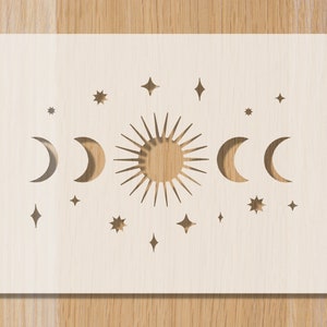 Peut inclure: Une découpe de papier blanche avec un motif de soleil, de lunes et d'étoiles. Le soleil a une forme d'étoile et les lunes sont en forme de croissant.