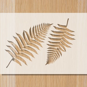 May include: A wooden wall art piece featuring two detailed fern leaf designs. The ferns are a warm brown color, set against a light beige background. The artwork is rectangular and has a natural, earthy aesthetic.