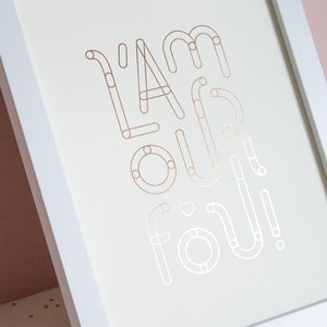 May include: A white framed print with the text "I'm our fou!" in rose gold foil lettering.