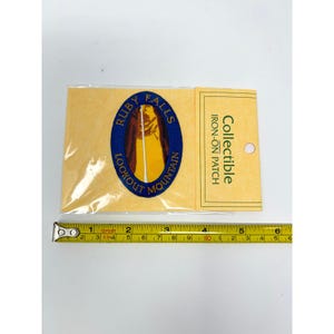 May include: An oval-shaped iron-on patch featuring a yellow waterfall graphic on a dark blue background with the text Ruby Falls Lookout Mountain. The patch is in clear packaging with a yellow card labeled Collectible Iron-On Patch and a 6-inch ruler.