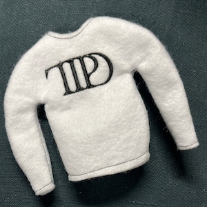 May include: White long-sleeved shirt with the word "TPD" embroidered on the front in black thread.