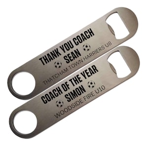 May include: Two silver bottle openers with black text. The top opener reads "THANK YOU COACH SEAN" with a soccer ball graphic. The bottom opener says "COACH OF THE YEAR SIMON" with a soccer ball graphic.