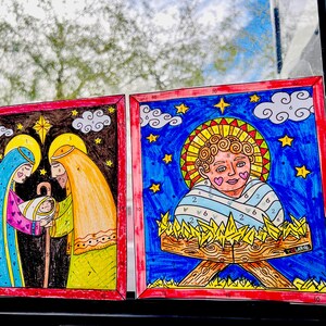 May include: Two framed illustrations of the Nativity scene. The first shows Mary, Joseph, and baby Jesus in a dark blue, yellow, and pink color scheme. The second shows baby Jesus in a manger with a blue and yellow color scheme.