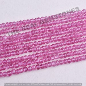 May include: A strand of pink faceted gemstone beads. The beads are small and round, and they have a translucent appearance.