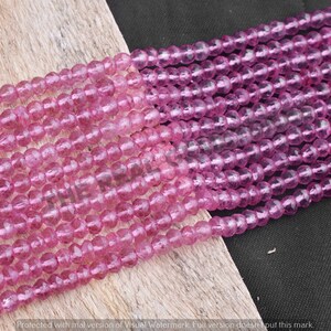 May include: A strand of pink faceted gemstone beads. The beads are round and have a translucent appearance.