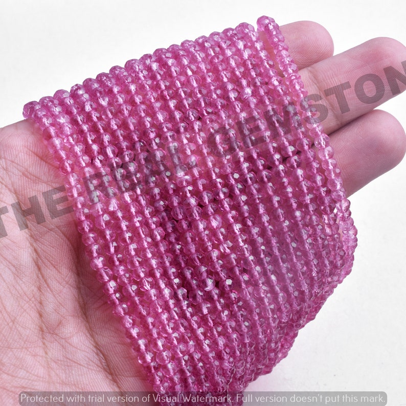 May include: A strand of pink faceted gemstone beads. The beads are small and round, and they are strung on a clear thread. The beads are all the same size and shape.
