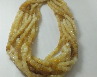 May include: A strand of yellow opal beads, each bead is a square shape with a slightly irregular cut. The beads are strung on a clear thread and are arranged in a loose, flowing pattern.