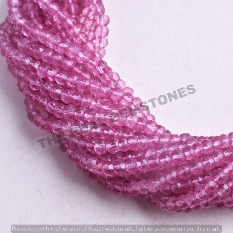 May include: A strand of pink faceted gemstone beads. The beads are small and round, and they have a translucent appearance. The beads are strung on a clear thread.