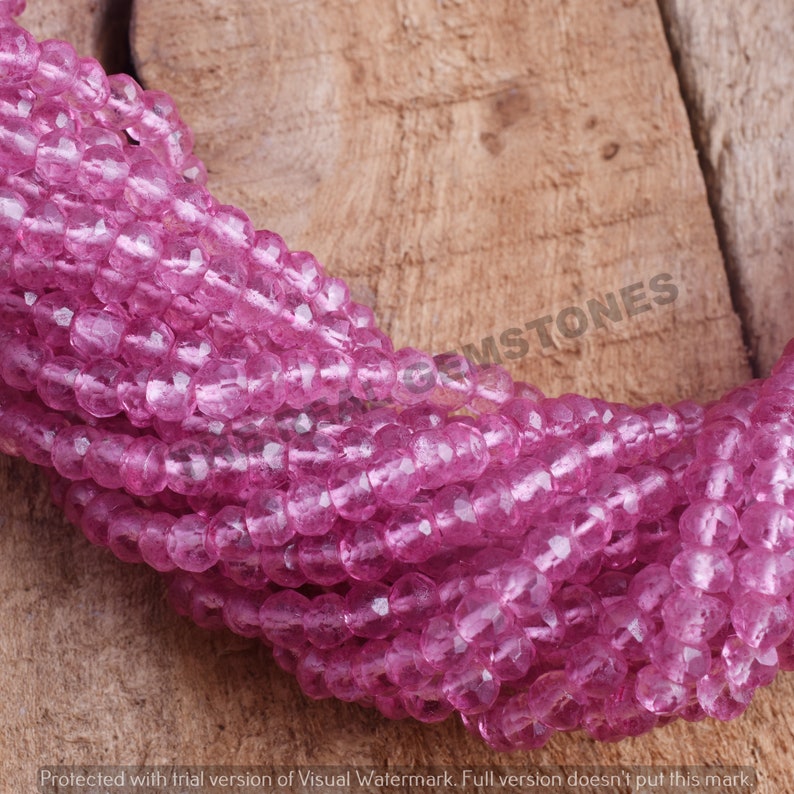 May include: A strand of pink faceted glass beads. The beads are translucent and have a slightly iridescent sheen.