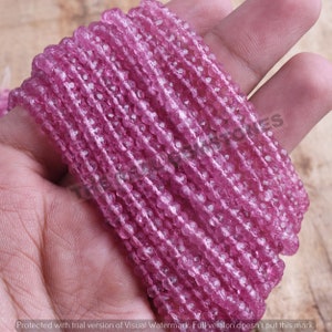 May include: A strand of pink faceted gemstone beads. The beads are small and round, and they are strung on a clear thread. The beads are all the same size and shape, and they are arranged in a straight line.