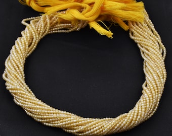May include: A strand of small, round, iridescent, light-colored beads with a yellow tassel.