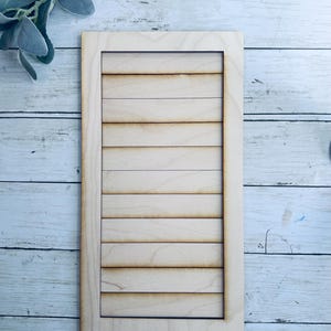 May include: A wooden shutter with a light brown finish and a rectangular frame. The shutter has 8 horizontal slats.