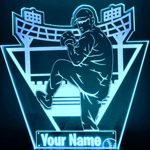 May include: A blue and white custom LED light depicting a baseball player pitching in a stadium. The light has a personalized nameplate that says "Your Name".