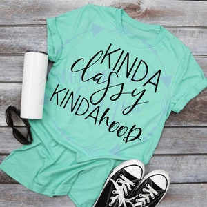 May include: A teal t-shirt with the text "Kinda Classy Kinda Hoop" in black script font.