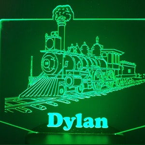 May include: Green illuminated sign with a line drawing of a steam locomotive and the name "Dylan" below it.