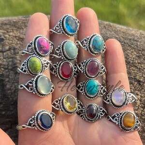 Op de afbeelding: Een verzameling van 15 zilveren ringen met verschillende gekleurde edelstenen. De ringen hebben een delicaat, versierd ontwerp en bevatten een verscheidenheid aan stenen, waaronder turquoise, amethist, robijn en citrien.