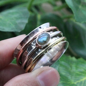May include: A silver spinning ring with three bands and a blue-green labradorite gemstone in the center.
