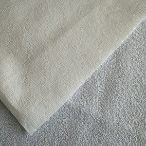 May include: Two pieces of fabric, one white and one gray, are laid on top of each other. The white fabric is smooth and the gray fabric is textured.