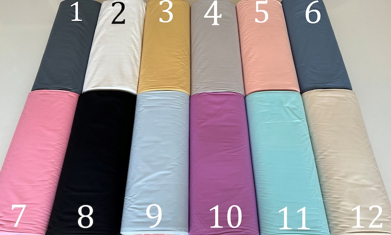 May include: Twelve rolls of fabric in various colors, numbered 1 through 12. The colors include gray, white, yellow, light gray, pink, blue, black, light blue, purple, turquoise, and beige.