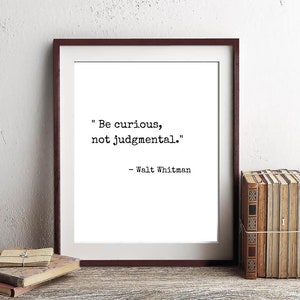 May include: A framed print with a black and white quote by Walt Whitman: "Be curious, not judgmental."