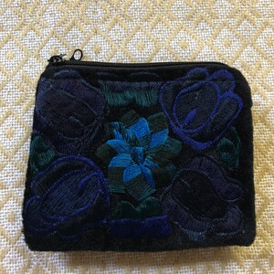 May include: A black velvet zippered pouch with embroidered blue and green floral designs.
