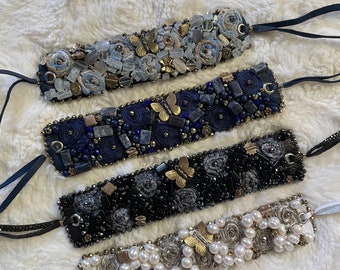 May include: Four beaded bracelets with different color schemes and embellishments. The bracelets feature a variety of materials, including pearls, beads, and fabric. Each bracelet has a unique design and color combination.