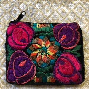 May include: A small black velvet coin purse with a zipper closure. The purse is embroidered with colorful flowers in shades of pink, purple, green, yellow, and orange.
