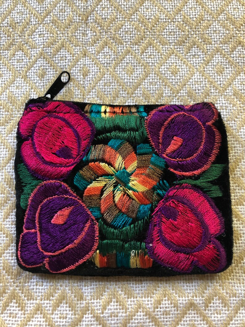 May include: A small black velvet coin purse with a zipper closure. The purse is embroidered with colorful flowers in shades of pink, purple, green, yellow, and orange.