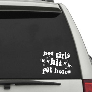 Puede incluir: Pegatina de vinilo blanco con el texto "hot girls hit pot holes" en una fuente retro. La pegatina está en la ventana trasera de un coche plateado.