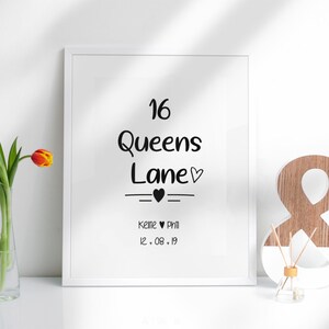 May include: A white framed print with black text that reads "16 Queens Lane" with a small heart symbol. Below the text is a line with a heart symbol and the text "Katie & Phil 12.08.19".