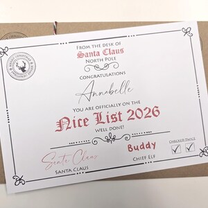 May include: A white certificate titled From the Desk of Santa Claus North Pole, featuring the text Congratulations Annabelle You Are Officially on the Nice List 2026. It includes a reindeer stamp, a signature, and a checked twice box.