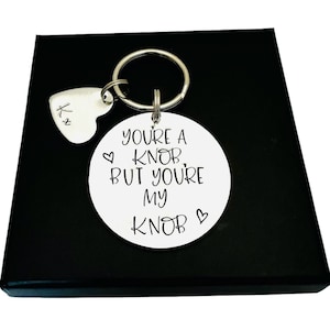 May include: A silver keyring with a round charm that says "You're a knob but you're my knob" and a small heart charm with the letter "K" engraved on it.