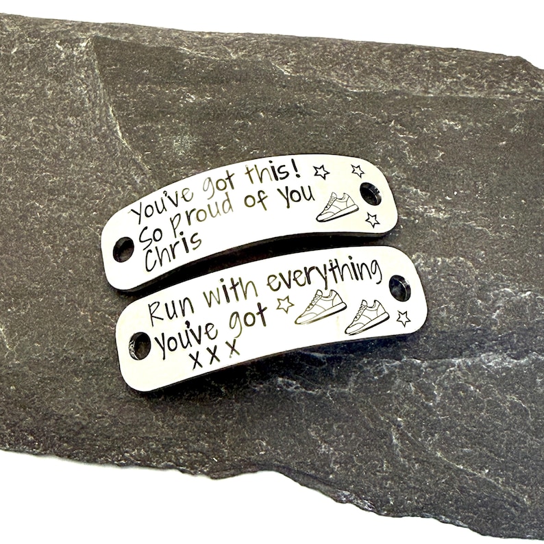 May include: Two silver-colored shoe tags with engraved text and running shoe illustrations. One tag reads "You've got this! So proud of you Chris" and the other says "Run with everything You've got X X X".
