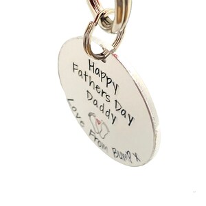 Peut inclure: Porte-cl&eacute;s argent&eacute; avec une &eacute;tiquette ronde qui dit "Happy Fathers Day Daddy Love From Bump X" avec un petit dessin de pied.