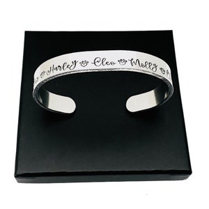 May include: Silver bracelet engraved with the names "Harley", "Cleo", and "Molly", along with paw prints and hearts.