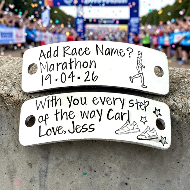 May include: Two silver metal shoe tags with black text. The top tag reads "Add Race Name? Marathon 19.04.26" with a runner graphic. The bottom tag says "With you every step of the way Carl Love, Jess" with shoe and star graphics.
