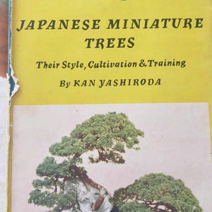 May include: A yellow book titled "Bonsai Japanese Miniature Trees" with the subtitle "Their Style, Cultivation & Training" by Kan Yashiroda. The cover features a photo of a bonsai tree in a brown pot.